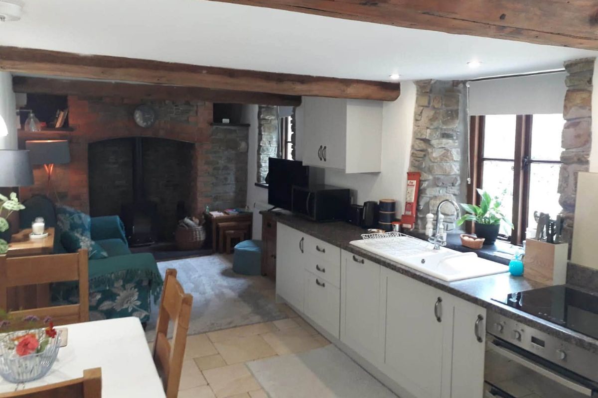 Cottage open-plan kitchen and living room with wood beams — original photo